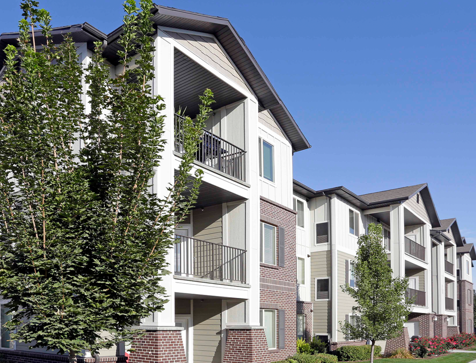 Modern multi-story apartment building with retail on the ground floor. Exterior shot on a sunny day.