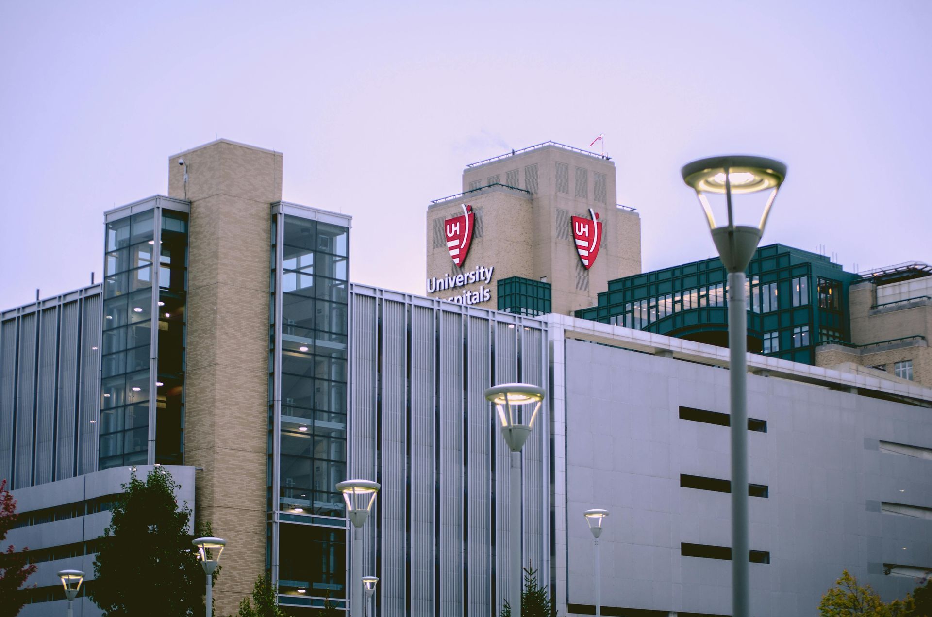 University building with shields on top, lit by streetlights against a cloudy sky.