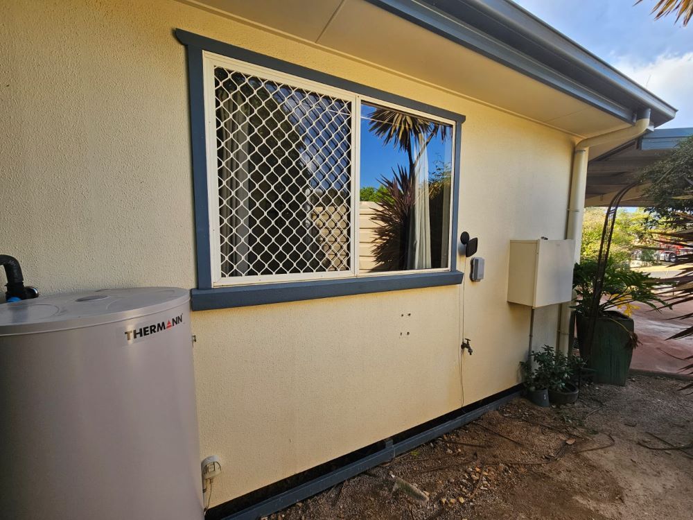 A white house with a window and a water heater on the side. — O & D House Wash & Cleaning Services in Highfields, QLD