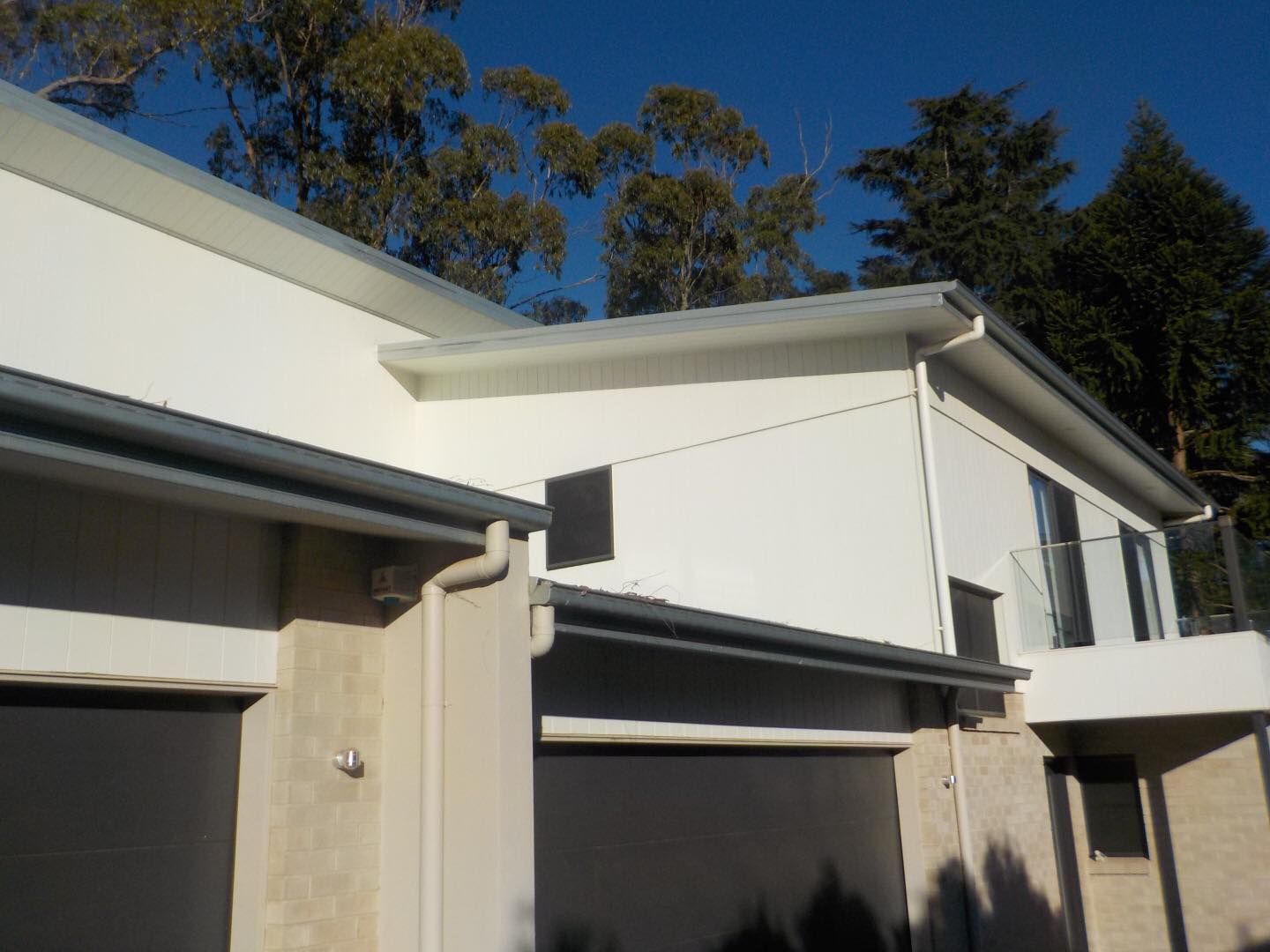 A House With Black Garage Doors and Trees — O & D House Wash & Cleaning Services in Westbrook, QLD