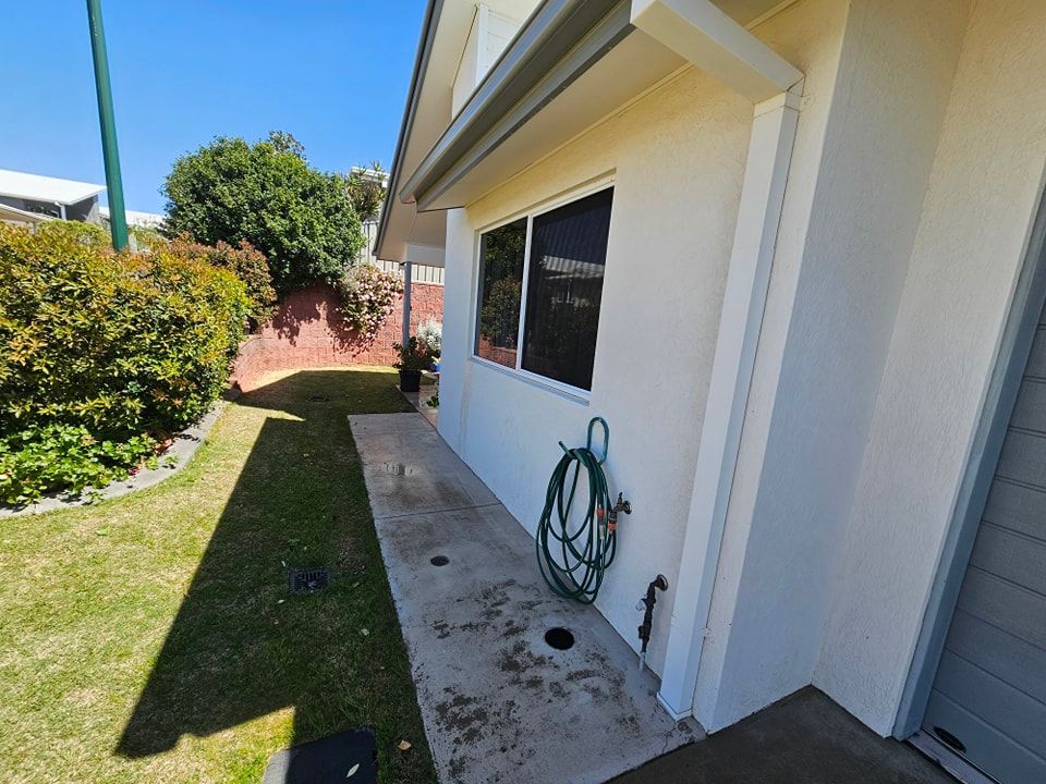 A white house with a hose attached to the side of it — O & D House Wash & Cleaning Services in Oakey, QLD