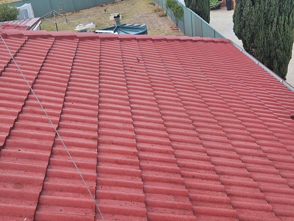 A red tiled roof of a house with a fence in the background. — O & D House Wash & Cleaning Services in Westbrook, QLD