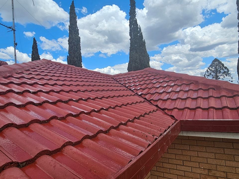 A red tiled roof with a blue sky and clouds in the background. — O & D House Wash & Cleaning Services in Westbrook, QLD