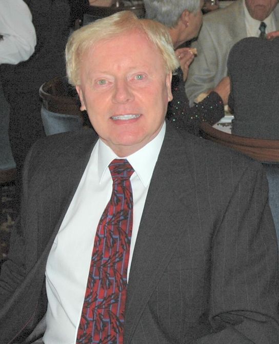 A man in a suit and tie is smiling for the camera