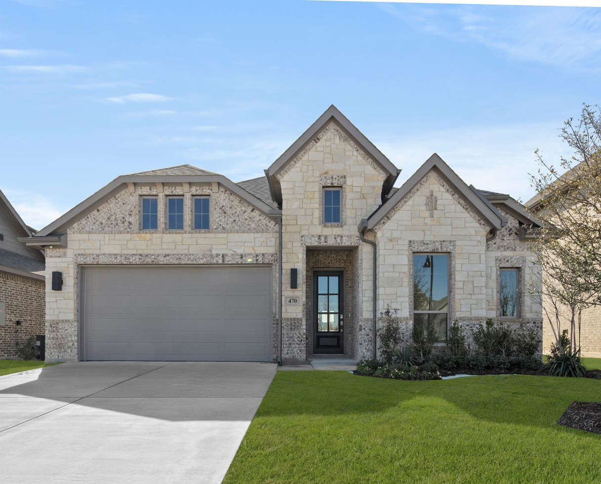 Two-story house with gray roof, stone facade, gray garage door, and lush green lawn on a sunny day.