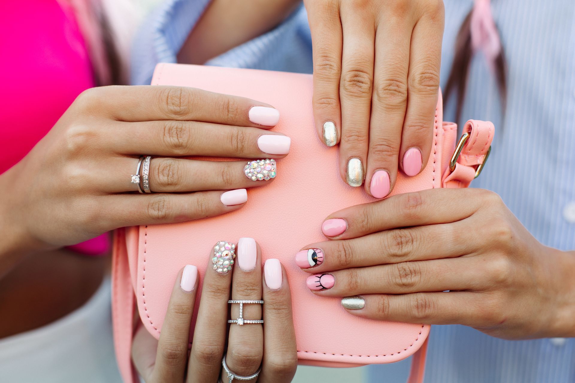 A woman with pink nails is holding a pink purse.