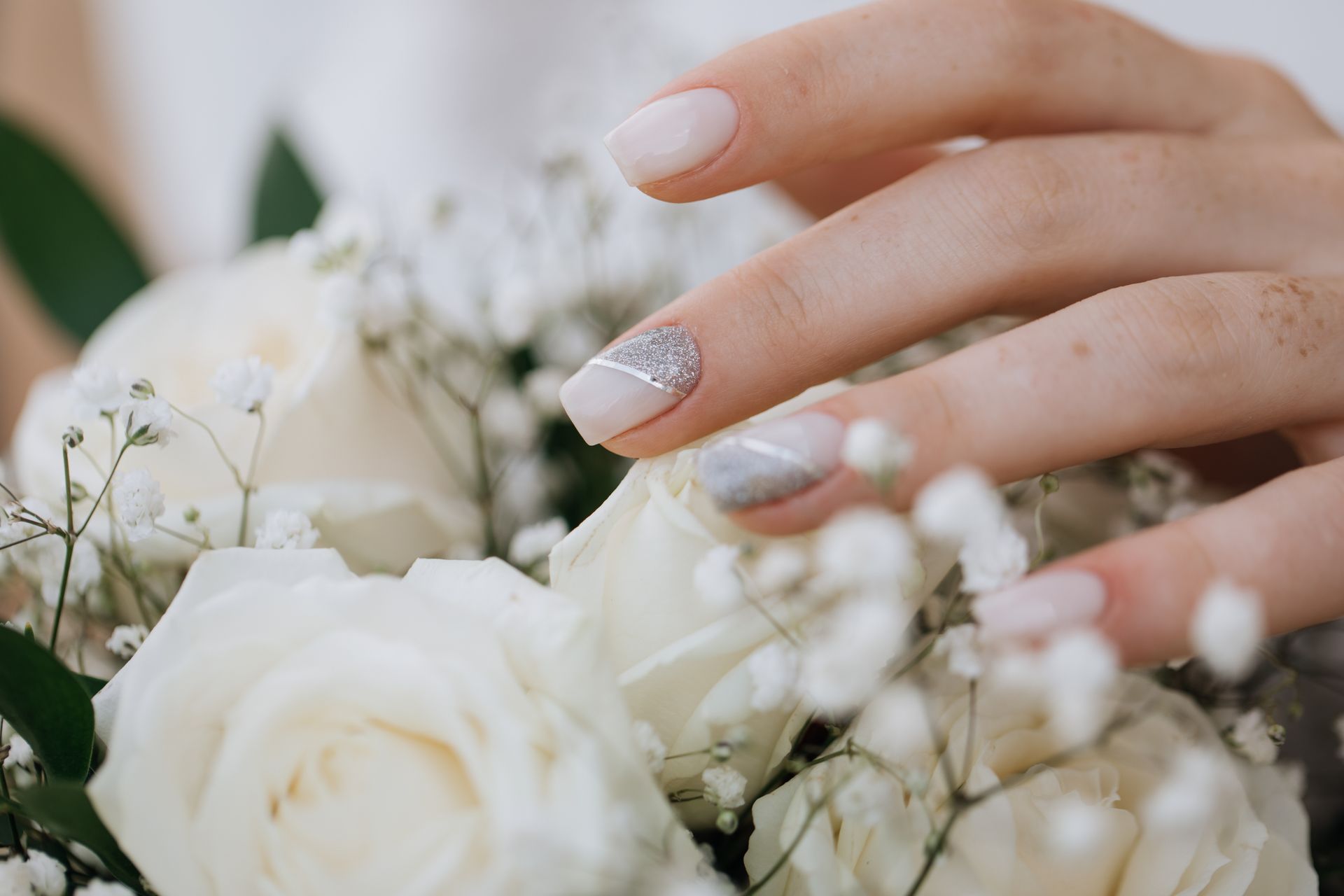 A close up of a woman 's hand holding a bouquet of white roses.