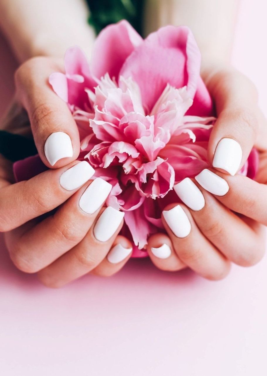 a woman with white nails holding pink flowers