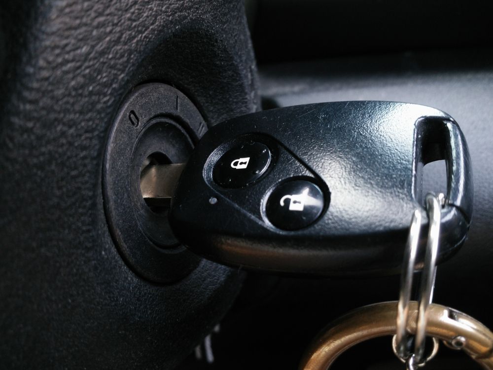 Car Key in The Ignition, Black Plastic Key with Remote Buttons, Close-Up Shot — Dependable Locksmiths In Harrington, NSW