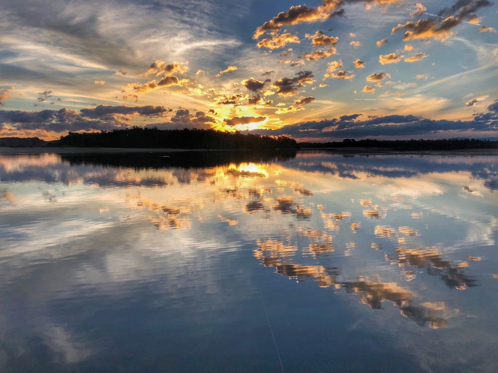 A Sunset Over A Lake With Clouds Reflected In The Water — Dependable Locksmiths In Old Bar, NSW