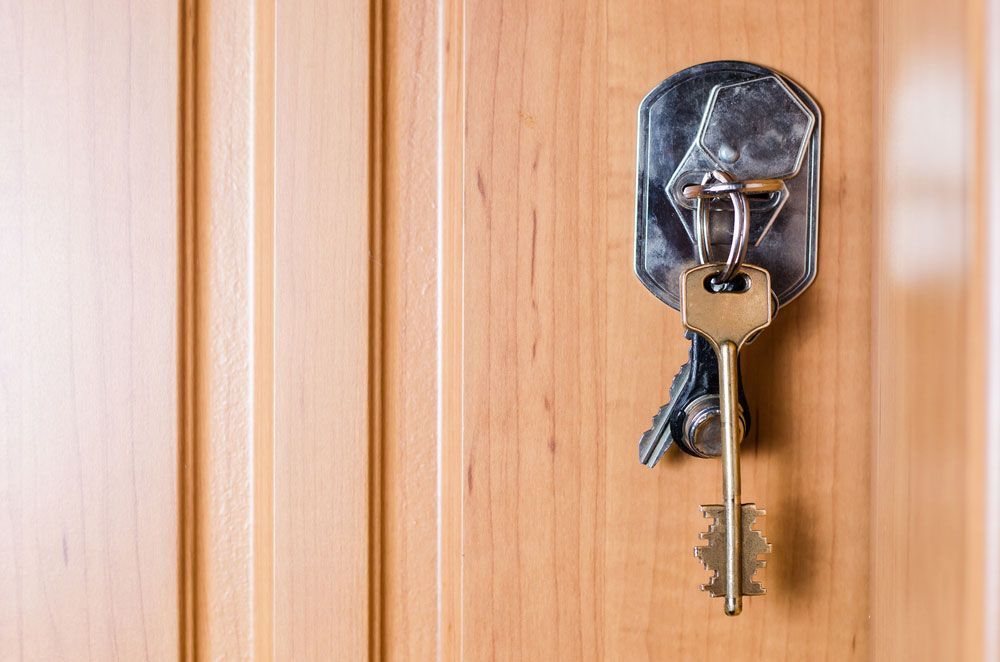 A Key Is Hanging On A Wooden Door — Dependable Locksmiths in Wingham, NSW
