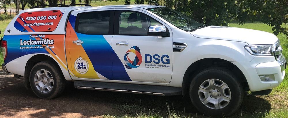 A White Truck With The Word Dsg On The Side Is Parked In The Grass — Dependable Locksmiths In Wingham, NSW