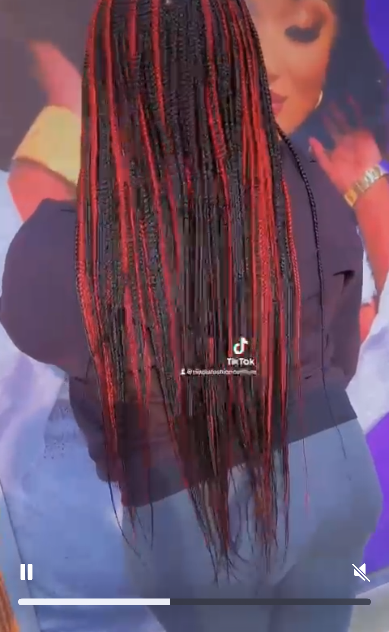 Woman with red and black braided hair, wearing a black shirt and jeans, standing near others.