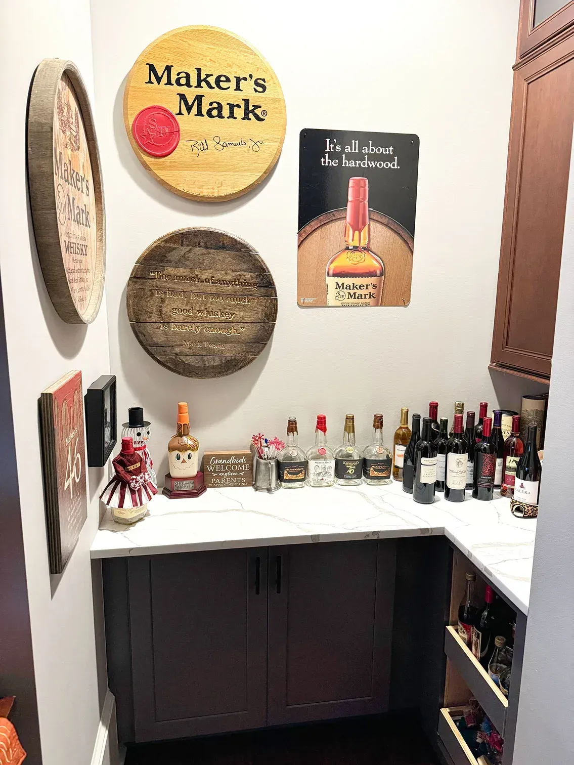 Home bar with bourbon and wine bottles, Maker's Mark decor, and a cabinet.