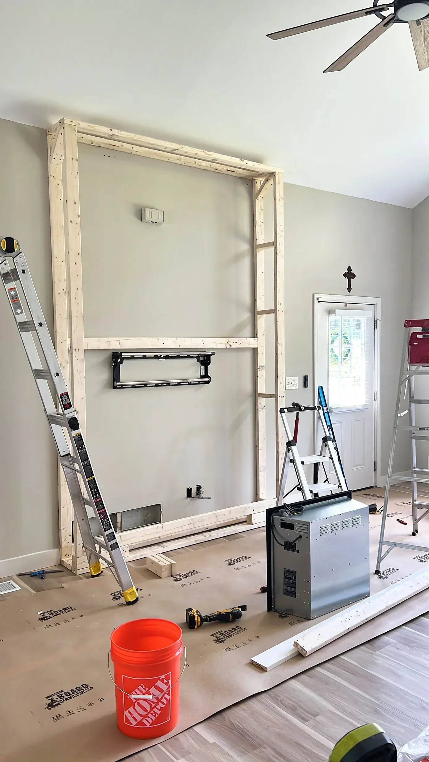 Wooden frame built on a wall, with a ladder, tools, and a bucket, suggesting home improvement.