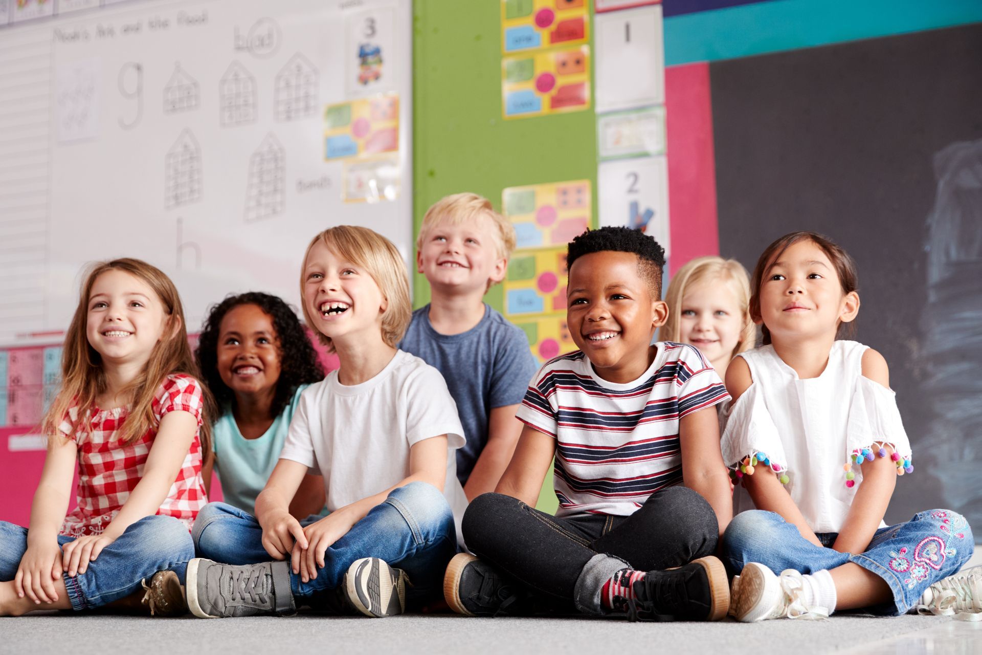 Group of elementary school pupils sitting on floor in classroom.