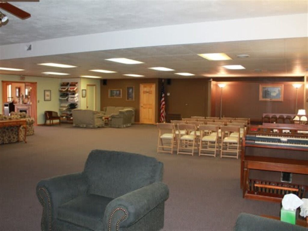 Spacious room with chairs, sofas, and an organ, likely a chapel or event space.
