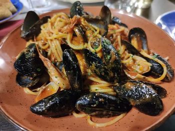 Piatto di pasta con cozze in salsa di pomodoro, servito su un piatto marrone.