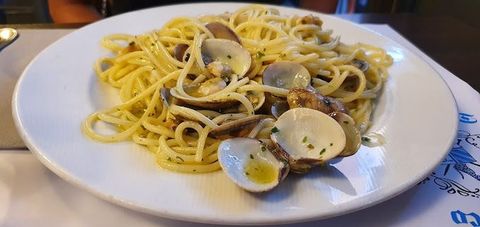 Spaghetti alle vongole serviti su un piatto bianco in un ristorante.