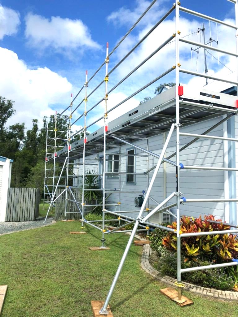 A house with scaffolding on the side of it is being painted.