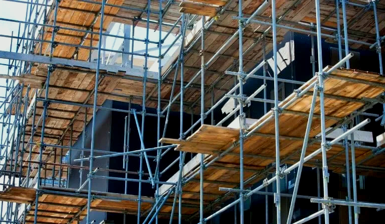 A building is being built with scaffolding and wooden planks.