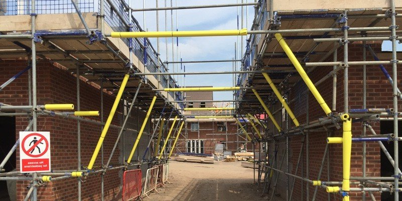 A construction site with scaffolding and a no intrusion sign.