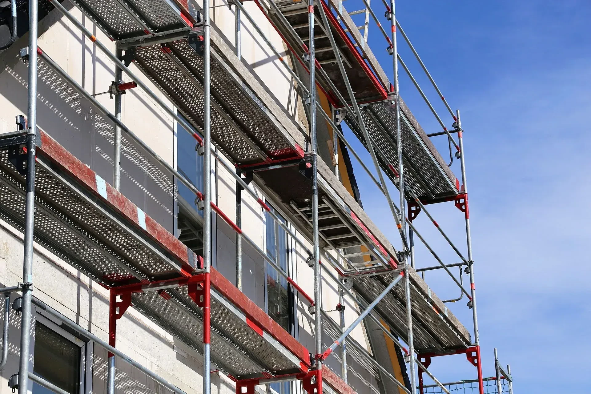 Scaffolding on a building's exterior, providing access for construction or repairs; against a blue sky.