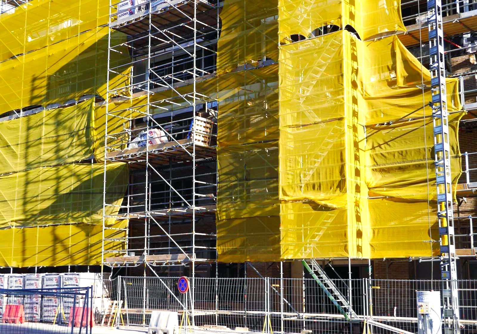 A large building is being built with yellow scaffolding around it.