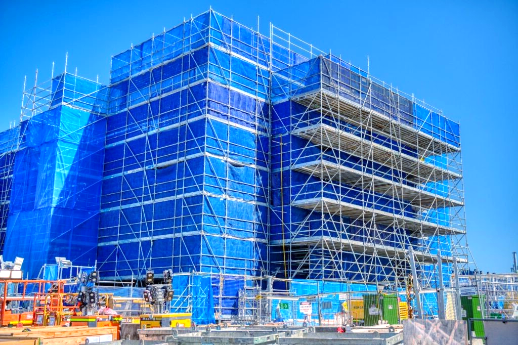 A large building is being built with blue scaffolding.
