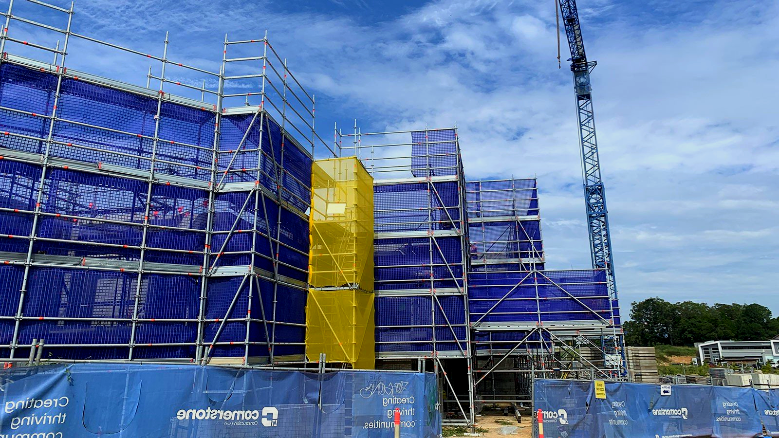 A large building is being built with scaffolding and a crane.