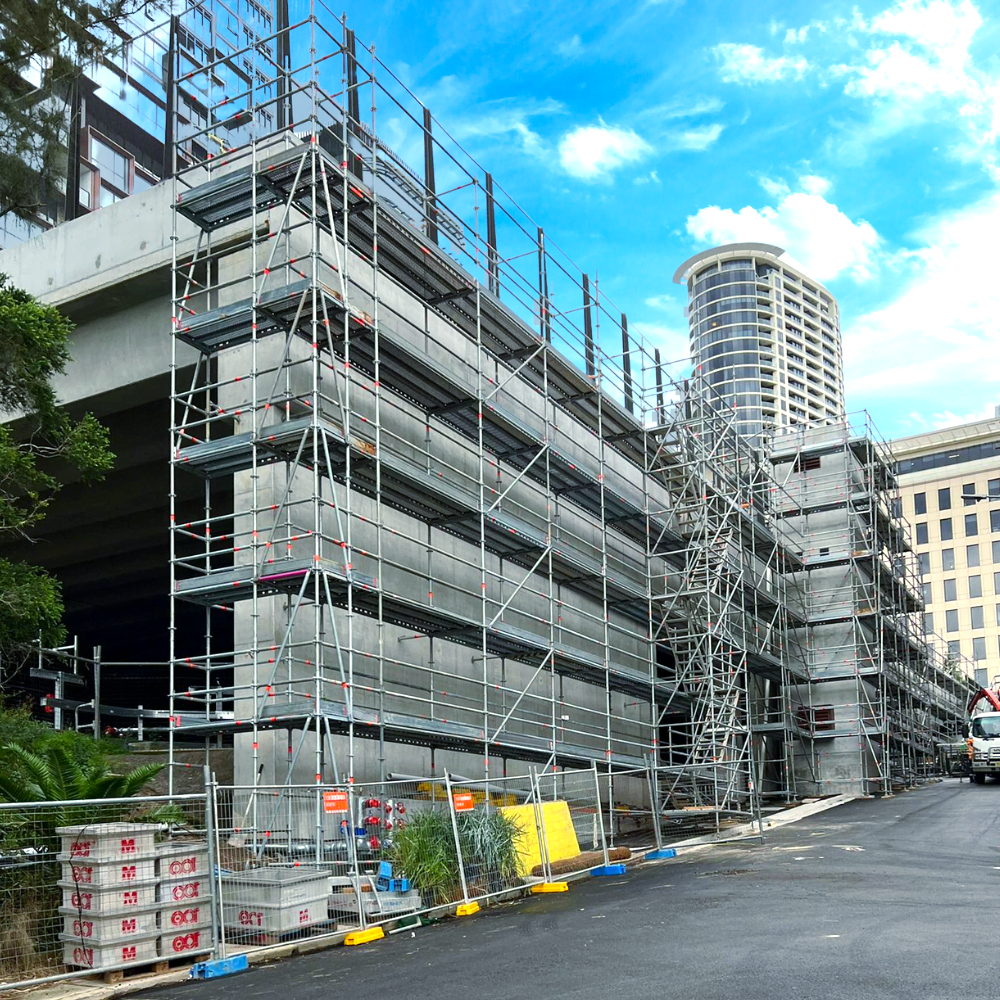 Scaffolding surrounds a building under construction, with a curved tower visible in the background.