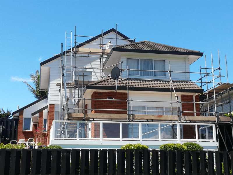 A house with scaffolding around it and a satellite dish on the roof.