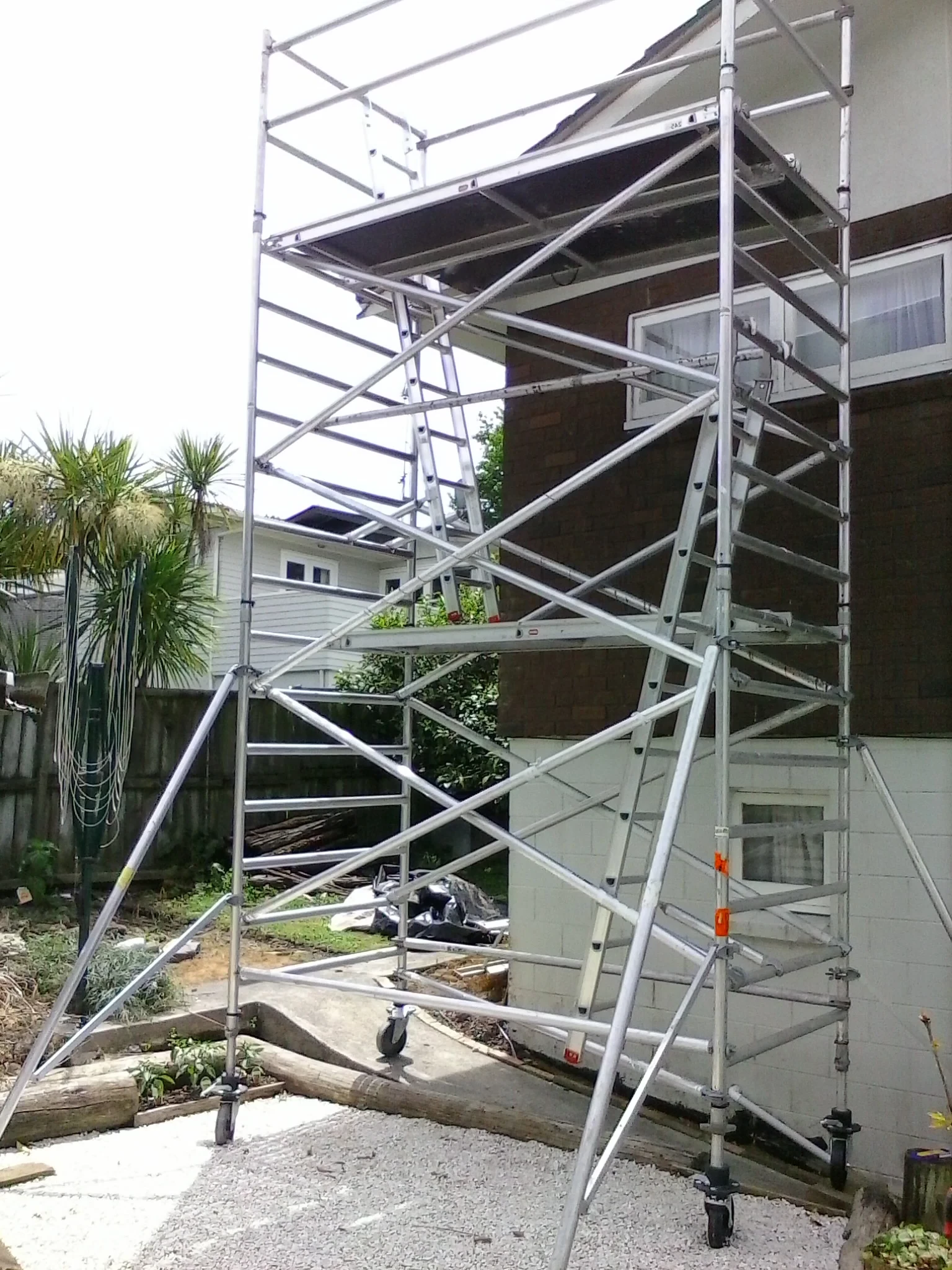 A scaffolding with a ladder on top of it is in front of a house.