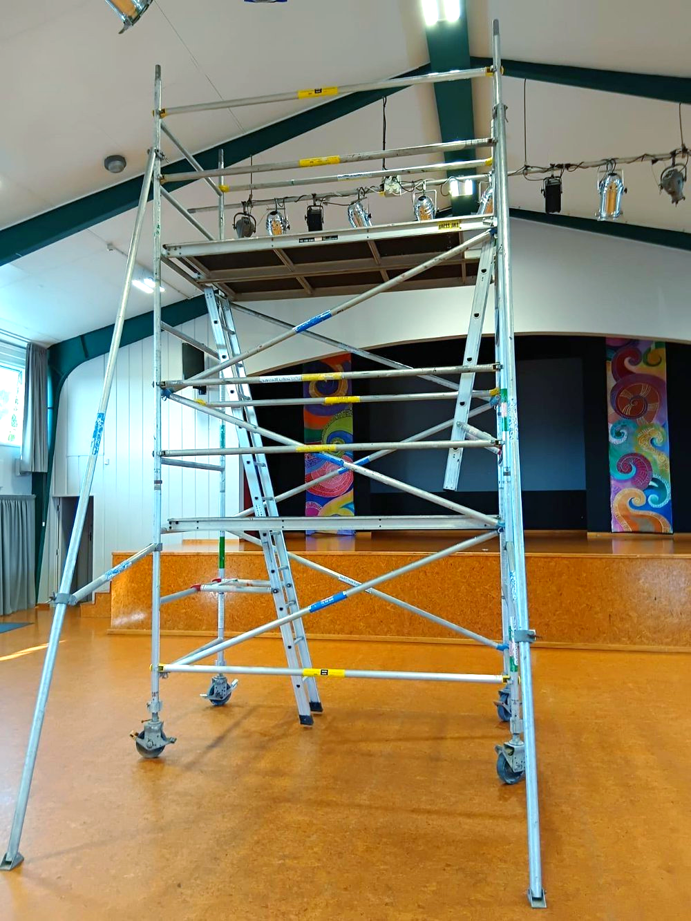 A large metal scaffolding with wheels is in an empty room.