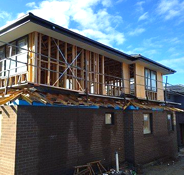 A brick house is being built with a wooden frame.