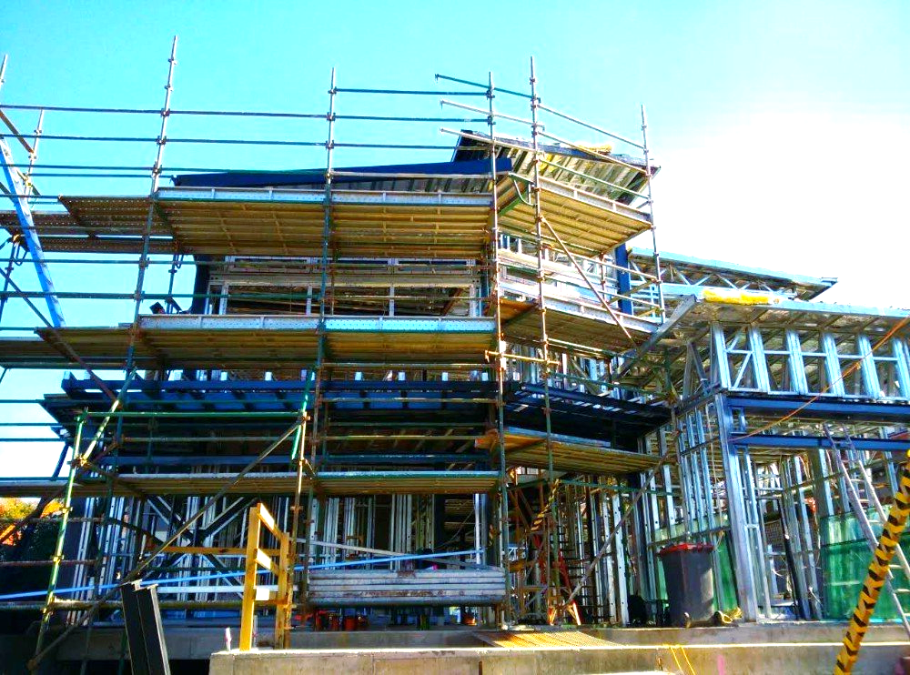 A large building under construction with scaffolding and a blue sky in the background.