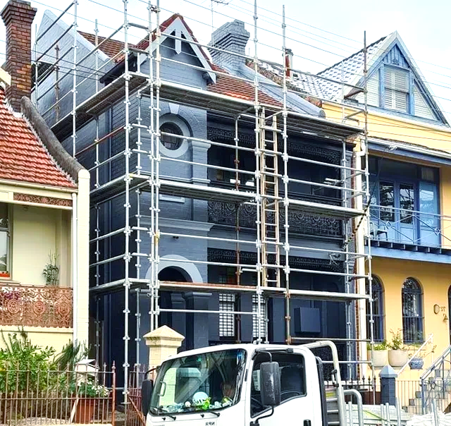 A truck is parked in front of a building with scaffolding around it.