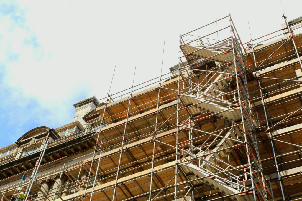 Scaffolding covering the facade of a building with ornate architectural details.