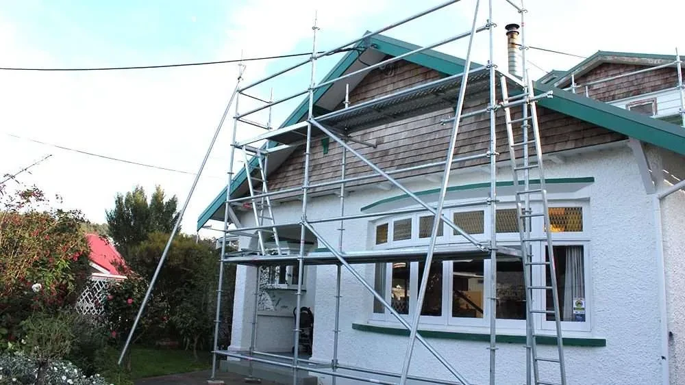 A white house with scaffolding on the side of it.