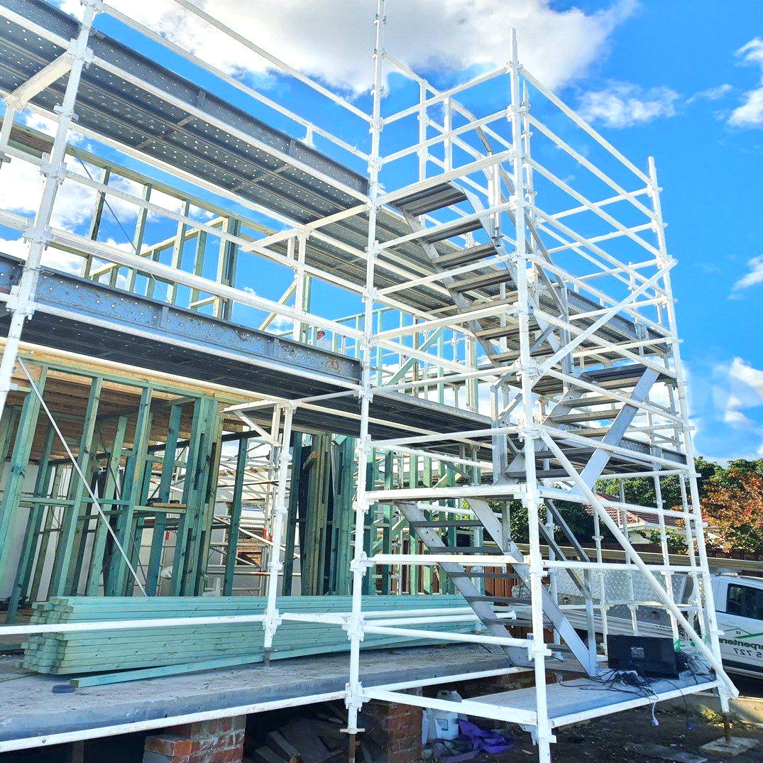 White scaffolding surrounding a building frame under construction on a sunny day.