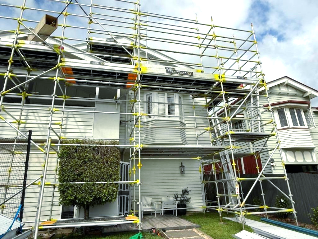 A house is being painted with scaffolding around it.
