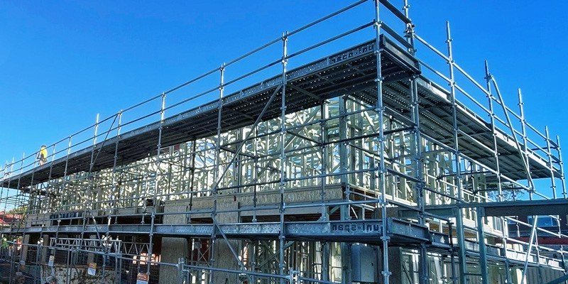 A building under construction with scaffolding and a blue sky in the background.
