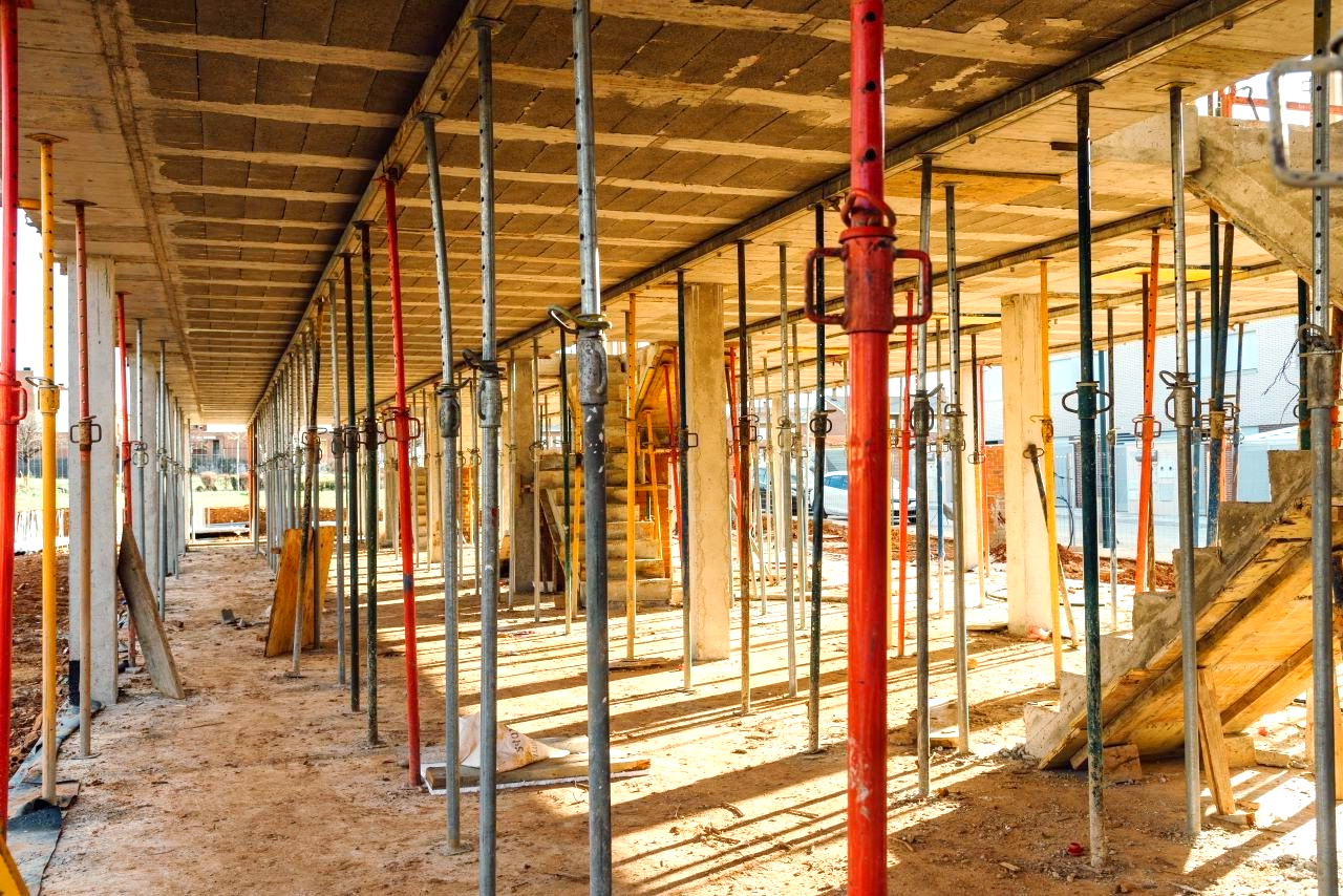 A building under construction supported by scaffolding underneath the building.