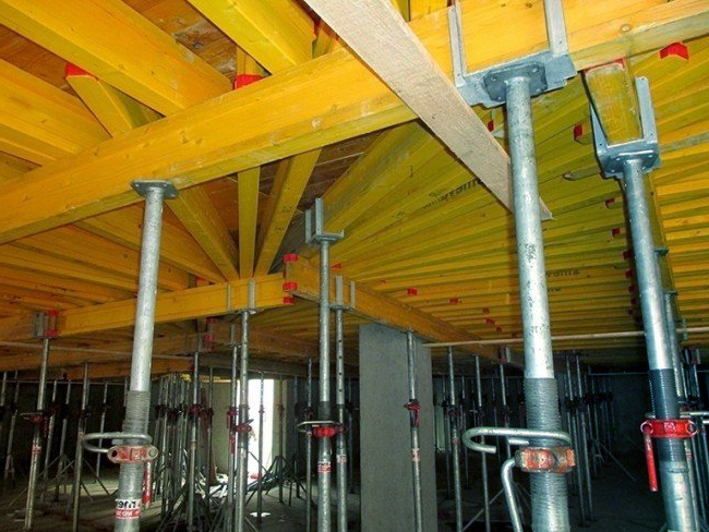 A building under construction with scaffolding and wooden beams under it.