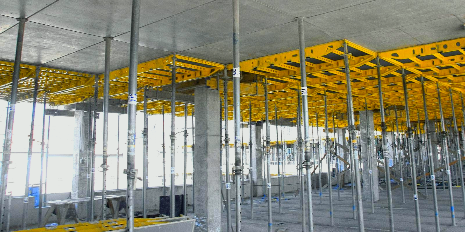 A building under construction with yellow and steel scaffolding under it.