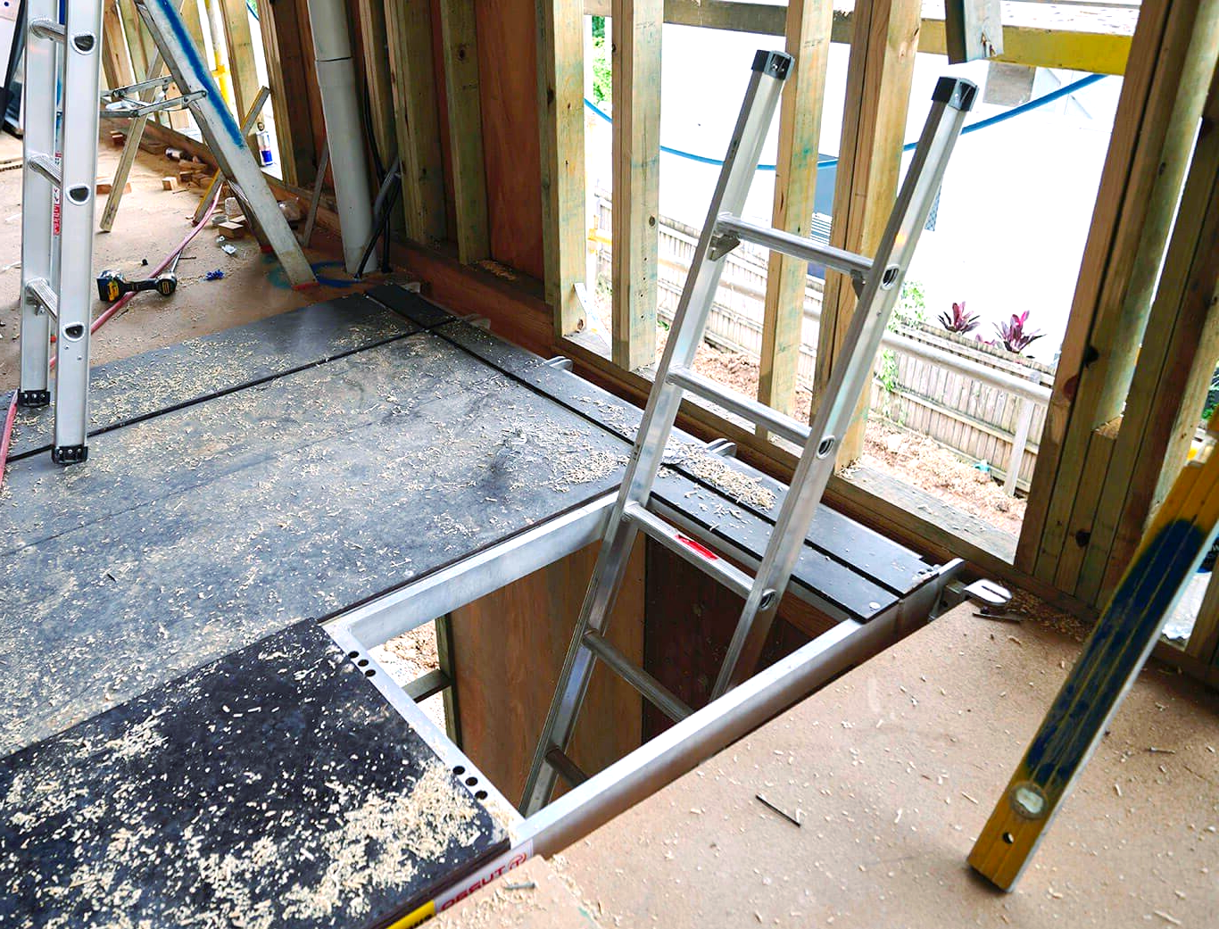 A ladder is sitting on top of a wooden floor next to a window.