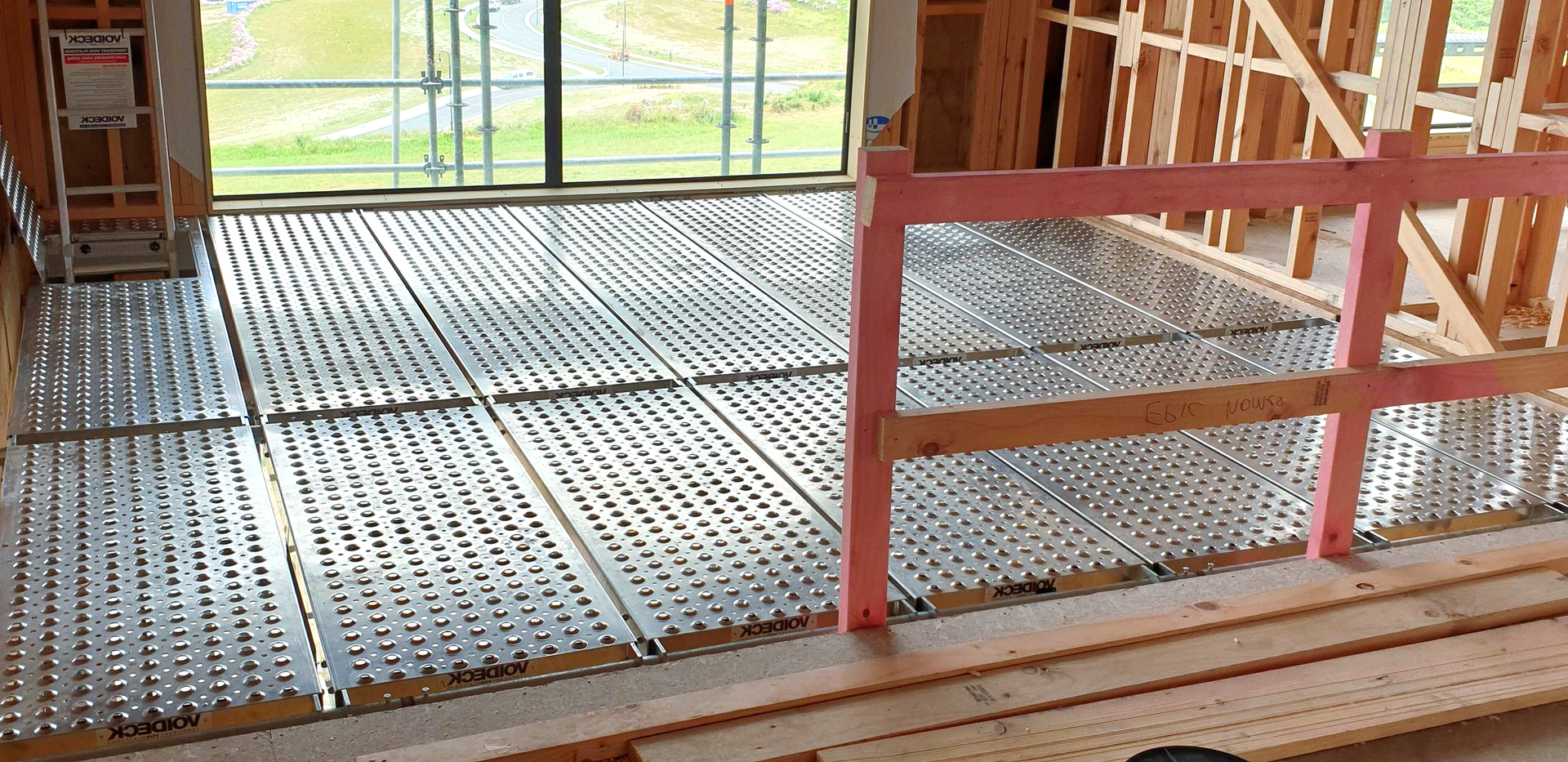 A building under construction with a metal floor and a wooden railing.