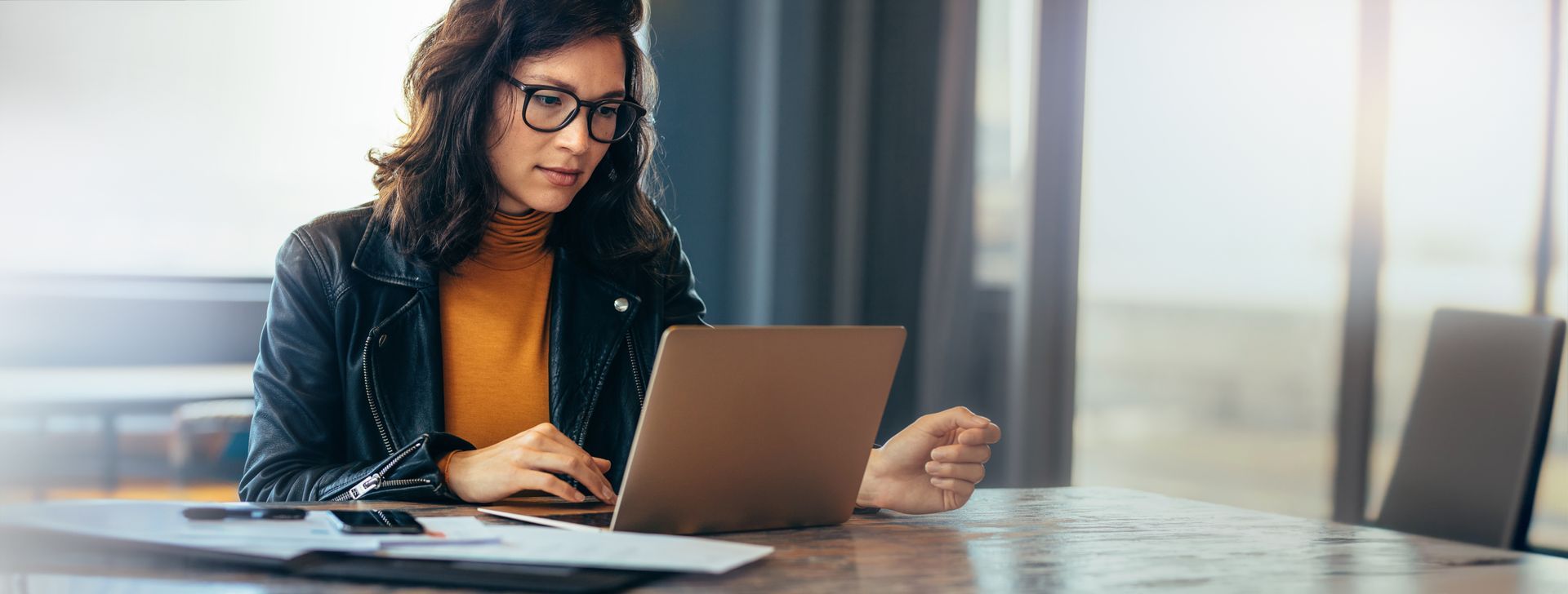 A woman is sitting at a table using a laptop computer.