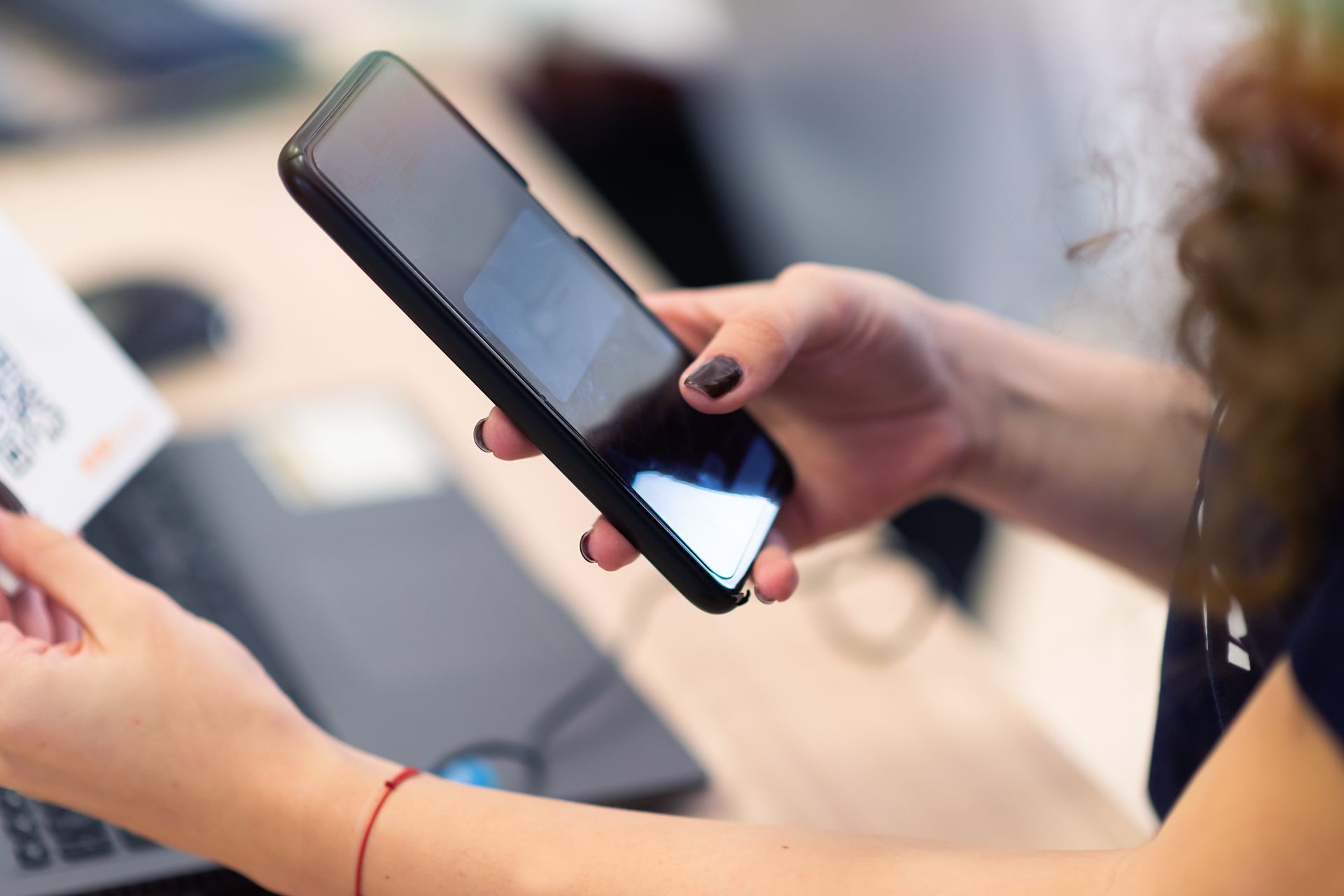 A woman is holding a cell phone and a credit card.