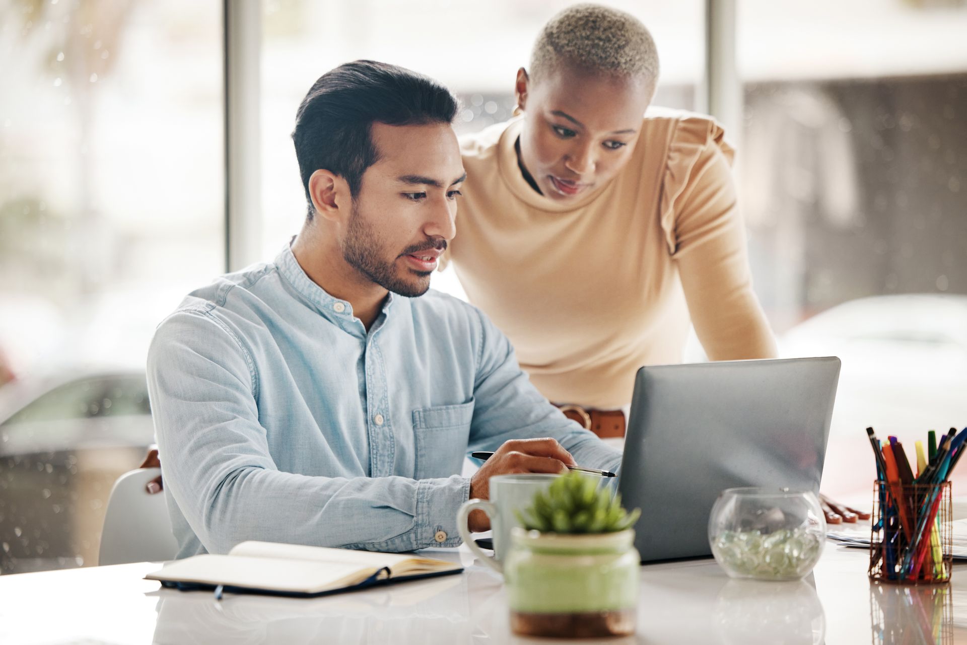 A man and a woman are looking at a laptop computer.